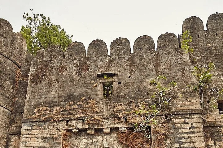 an old stone fort wall with crenellations and a small opening