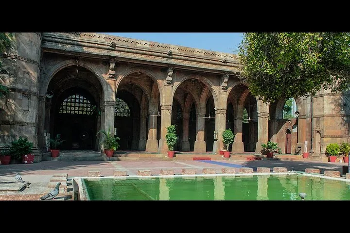 a courtyard with an arched portico and a small green pool